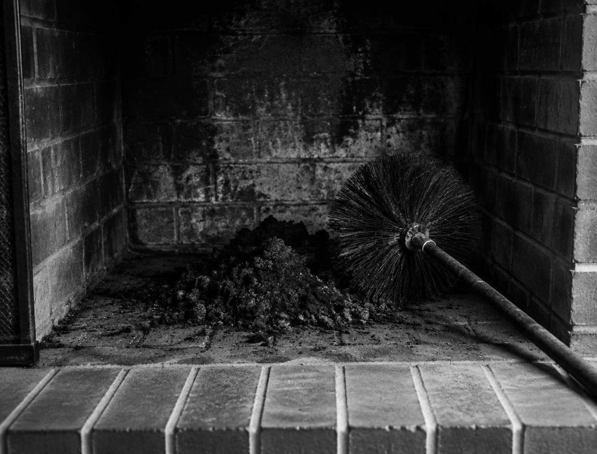 Chimney sweep brush in a cleaned fireplace